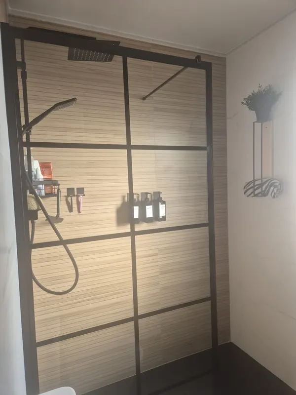 Baño con ducha de obra y mampara negra en Granada — Grupo Renovame