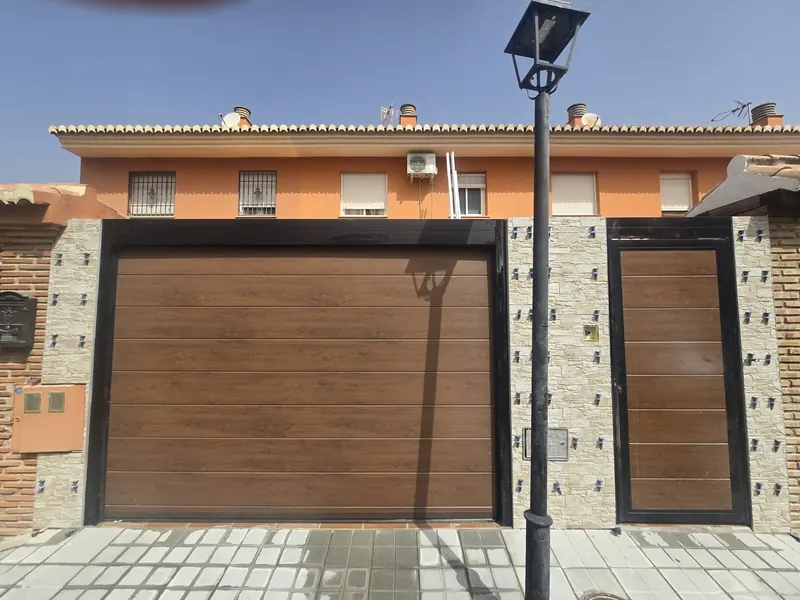 Entrada de adosado con puerta de garaje y aplacado de piedra en Granada — Grupo Renovame